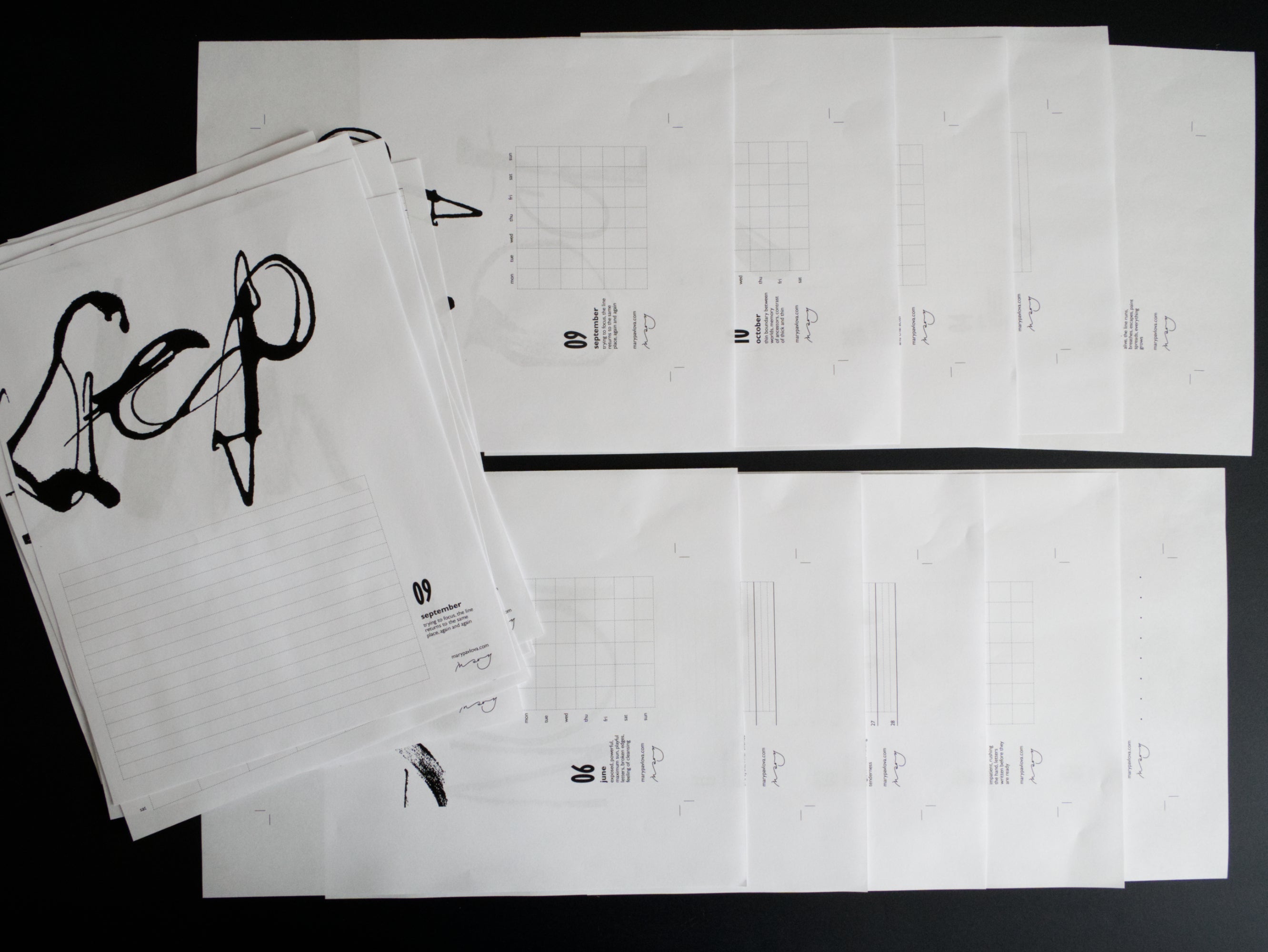 Set of black and white printed calendar sheets on a dark background