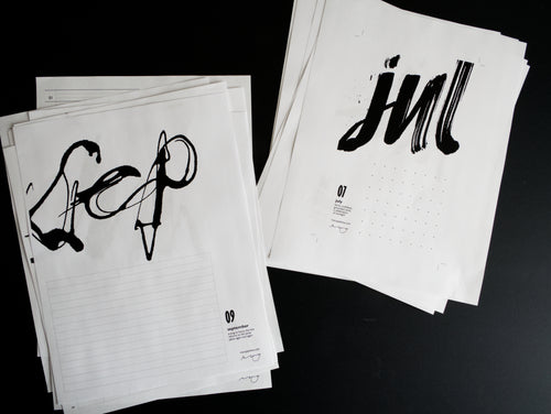 Twenty sheets of paper with black calligraphy on a dark background