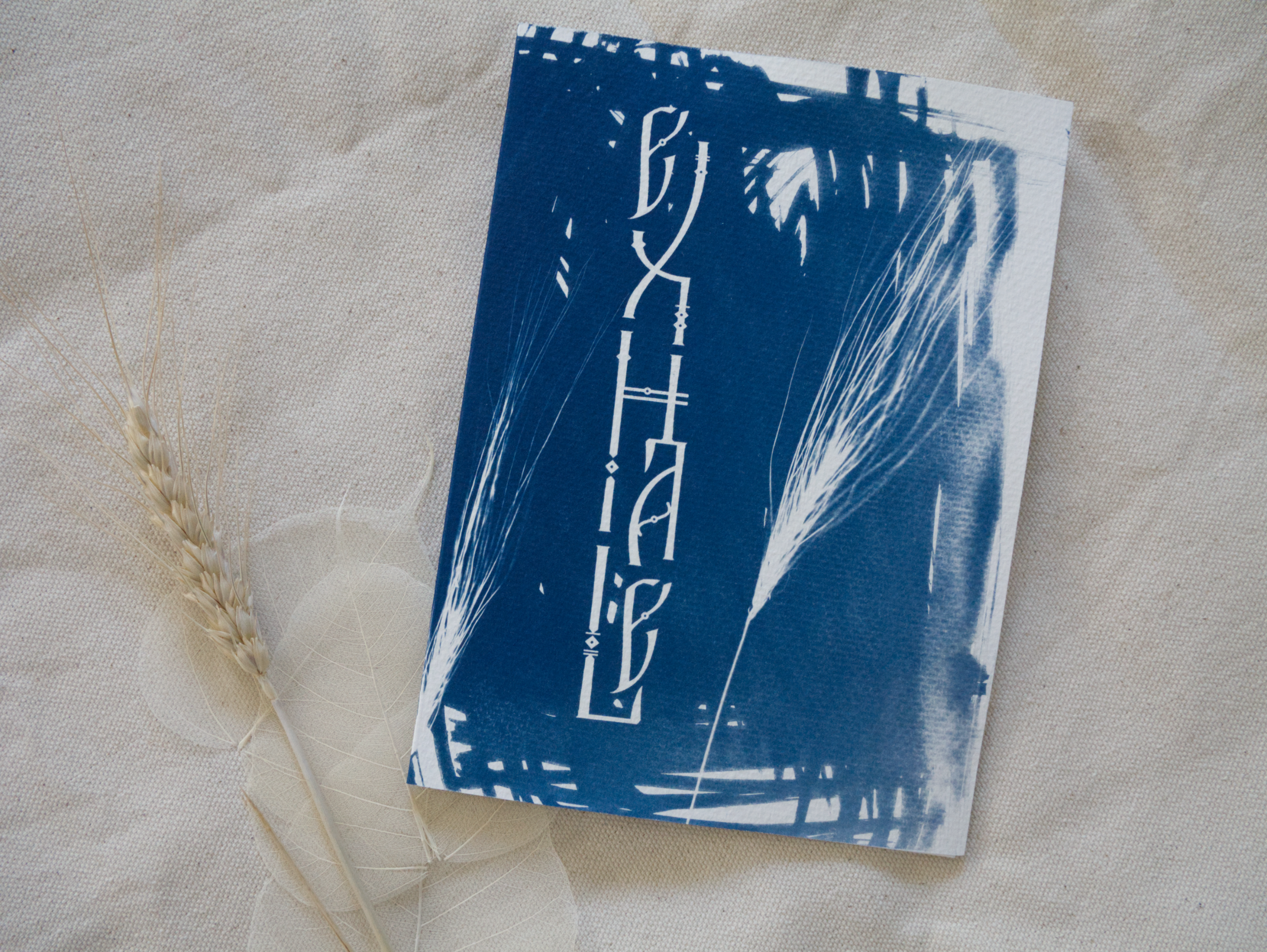 Blue and white abstract cyanotype greeting card with lettering Exhale on a beige fabric background