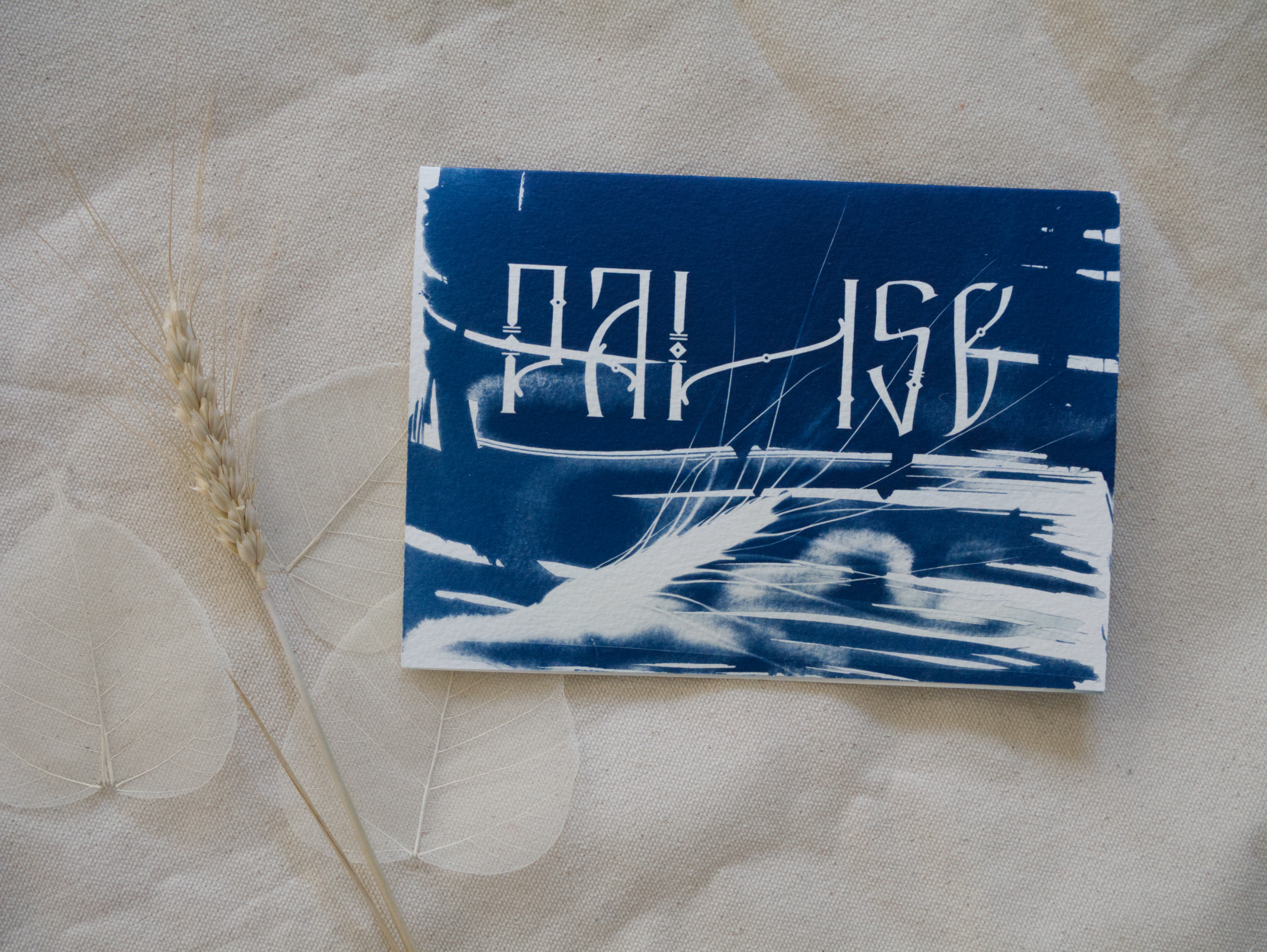 Blue and white abstract cyanotype greeting card with lettering Pause on a beige fabric background