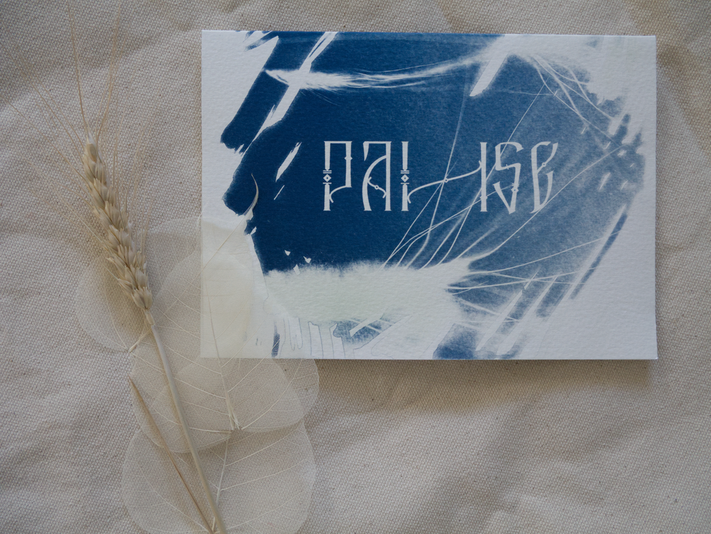Blue and white abstract cyanotype greeting card with lettering Pause on a textured beige surface