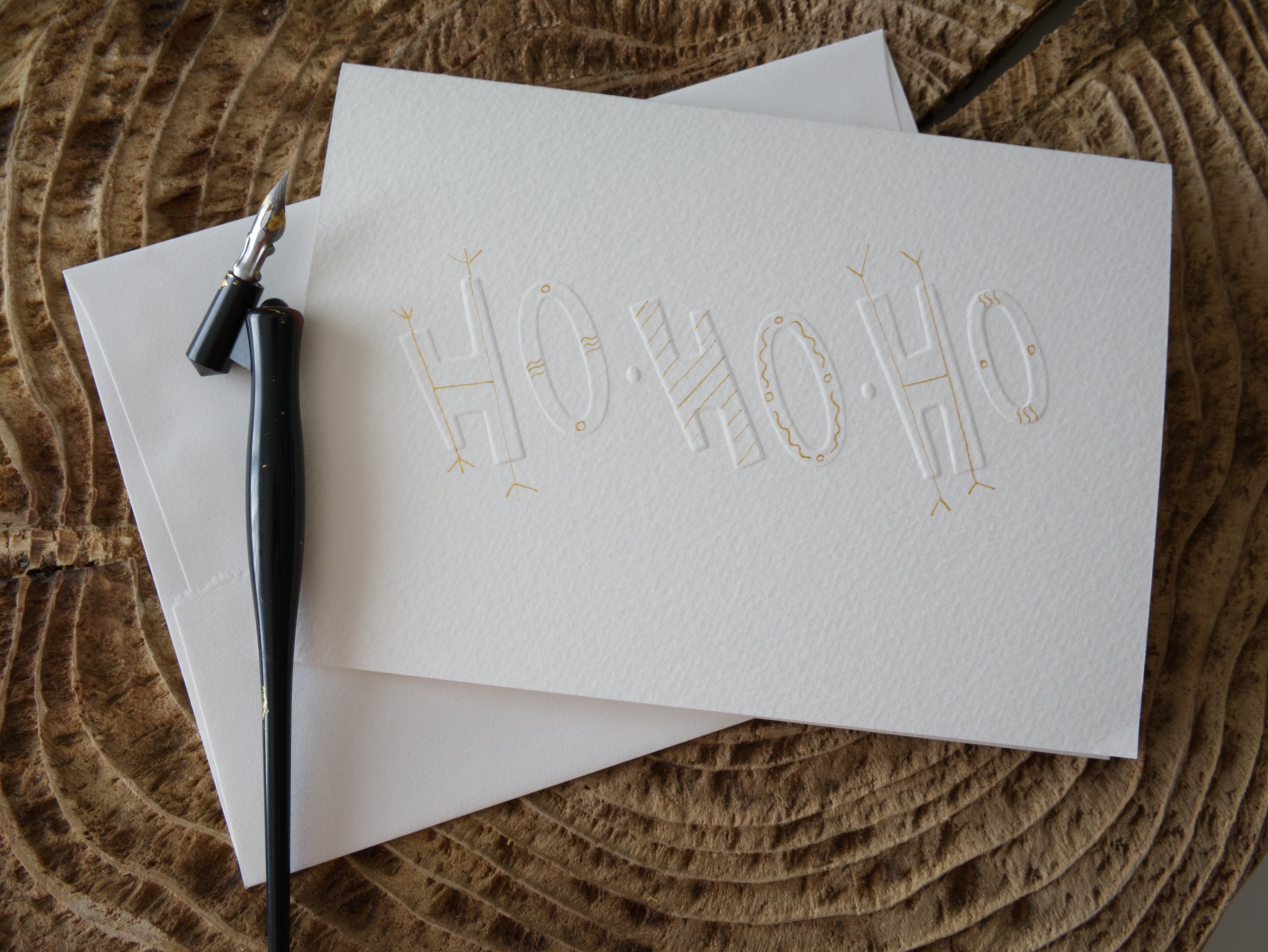 White greeting card with 'HO HO HO' embossed text and gold decorations