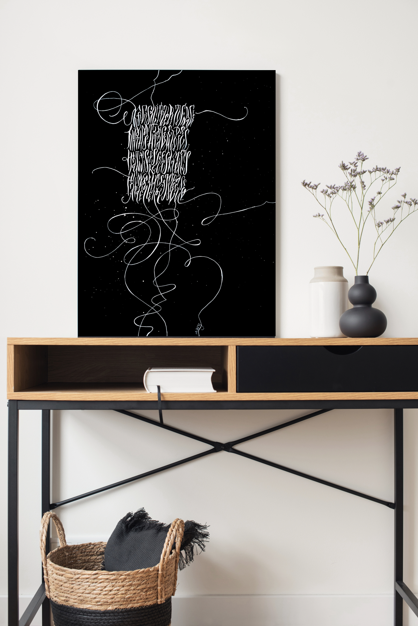White Calligraphy art on black canvas standing on the table
