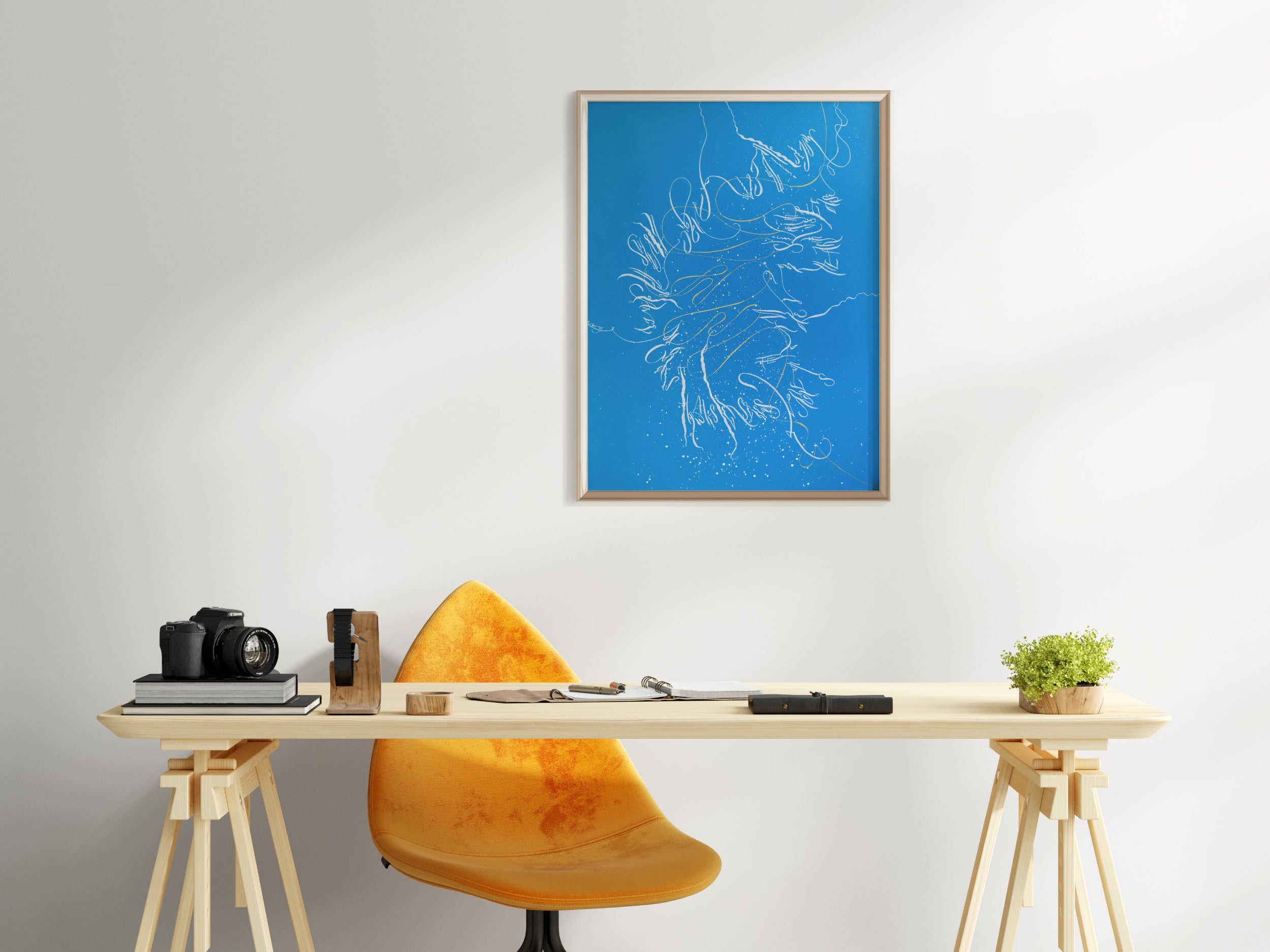 Modern office setup with a desk, chair, and framed artwork on a white wall.