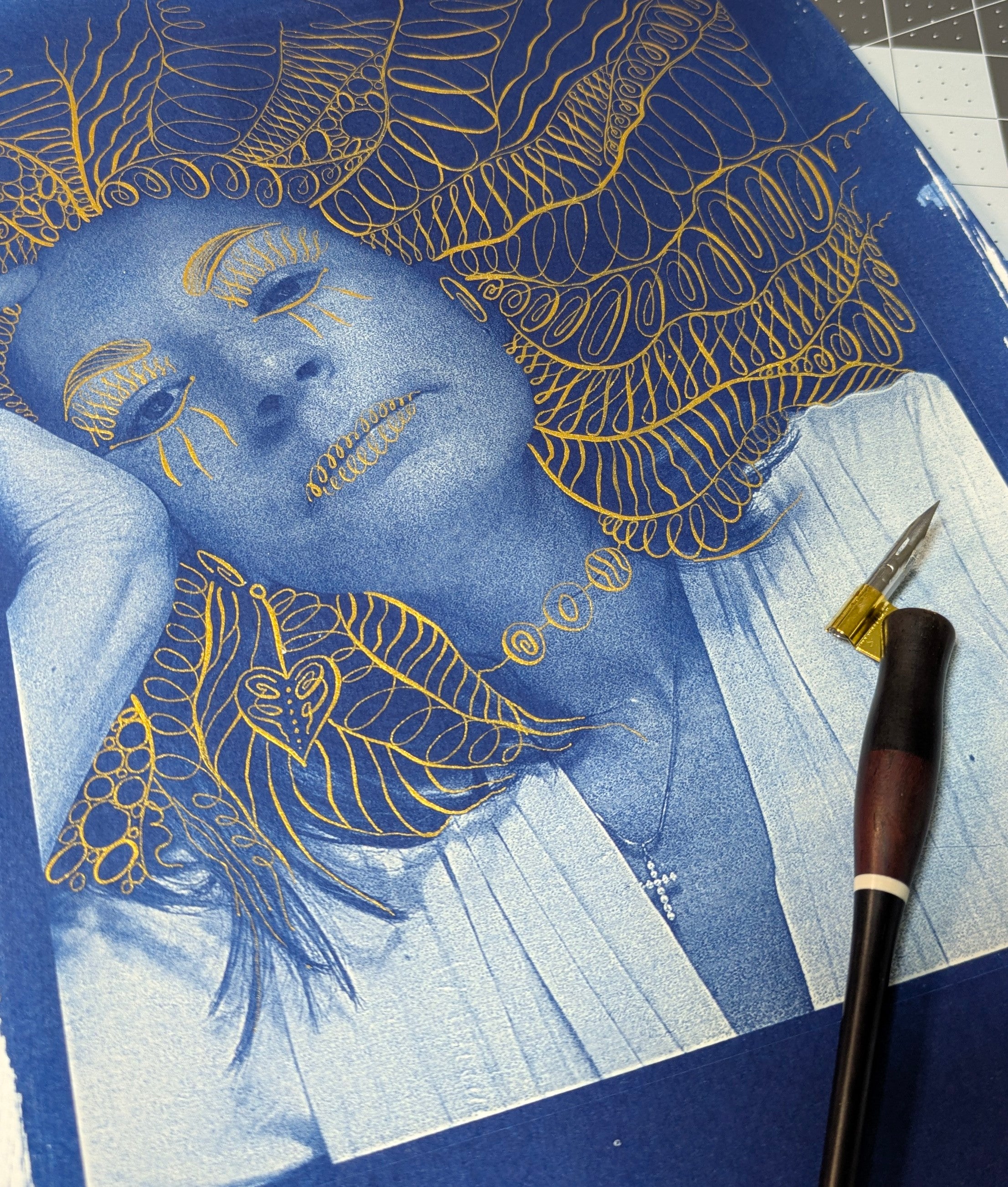 Blue and gold artistic illustration of a face with decorative elements on a blue surface.