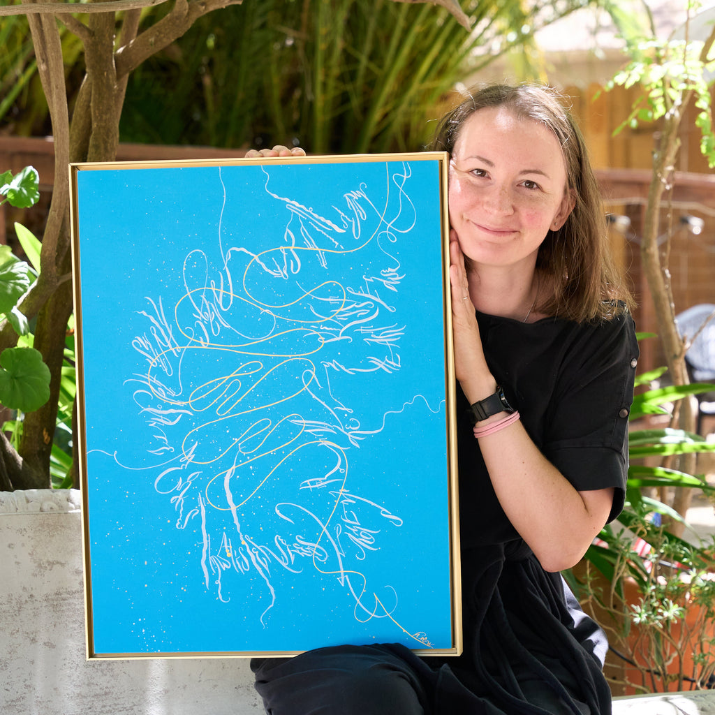 Mary Pavlova holding a large blue drawing of hands outdoors