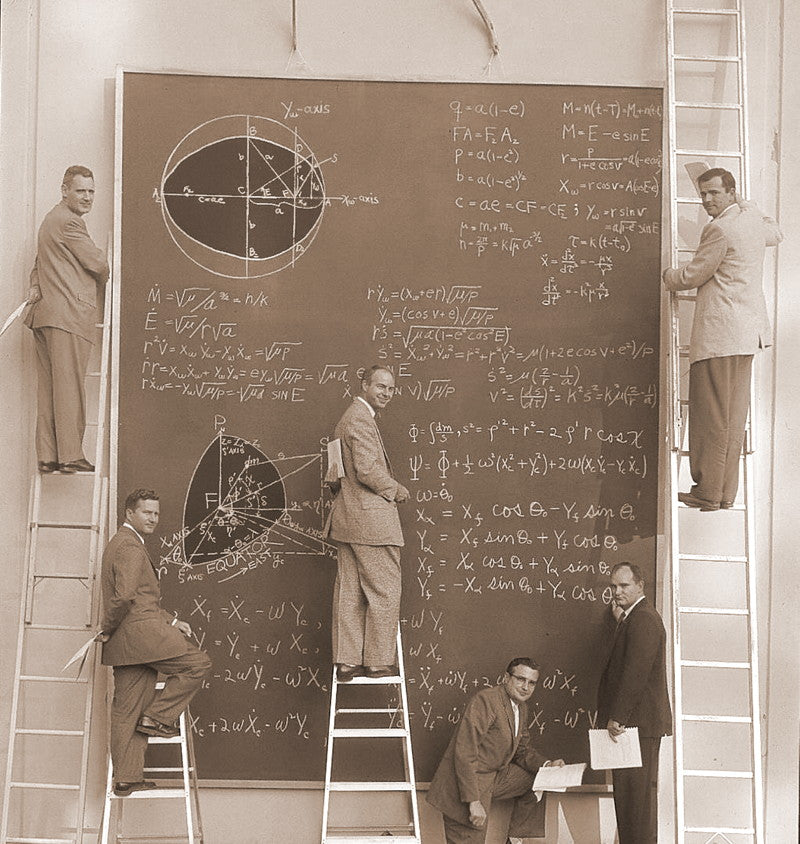 Scientists on ladders writing orbital mechanics equations across a massive chalkboard, turning the wall into a working surface for thought at Systems Laboratories, California, 1957